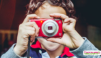 Niño con una cámara digital apuntando hacia el frente y a punto de hacer una fotografía